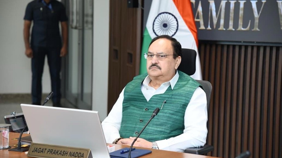 Jagat Prakash Nadda seated at a desk with a laptop and nameplate, national flag behind