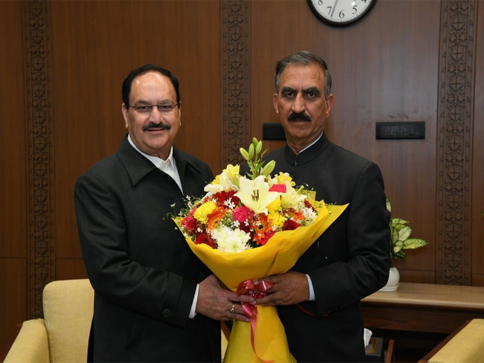 Jagat Prakash Nadda and Sukhvinder Singh Sukhu holding a bouquet in a wood-panelled office
