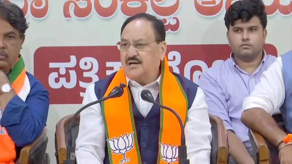Jagat Prakash Nadda speaking at a press conference table with microphones