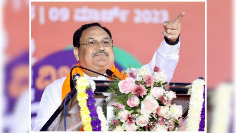 Jagat Prakash Nadda speaking at a flower-decked lectern and pointing upward