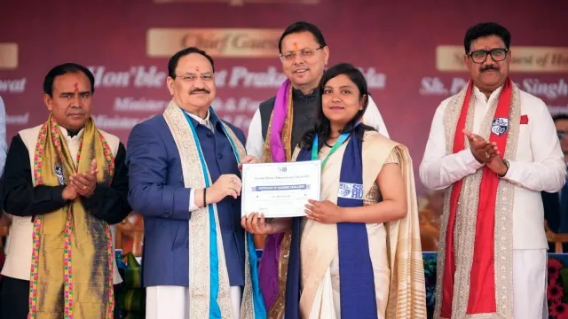 Jagat Prakash Nadda handing a certificate to a graduate, with Pushkar Singh Dhami and others on stage